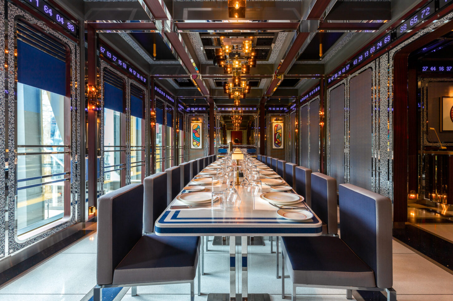 Restaurant interior with long dining table, patterned ceiling lights, and colourful wall art — Bob Bob Ricard, London