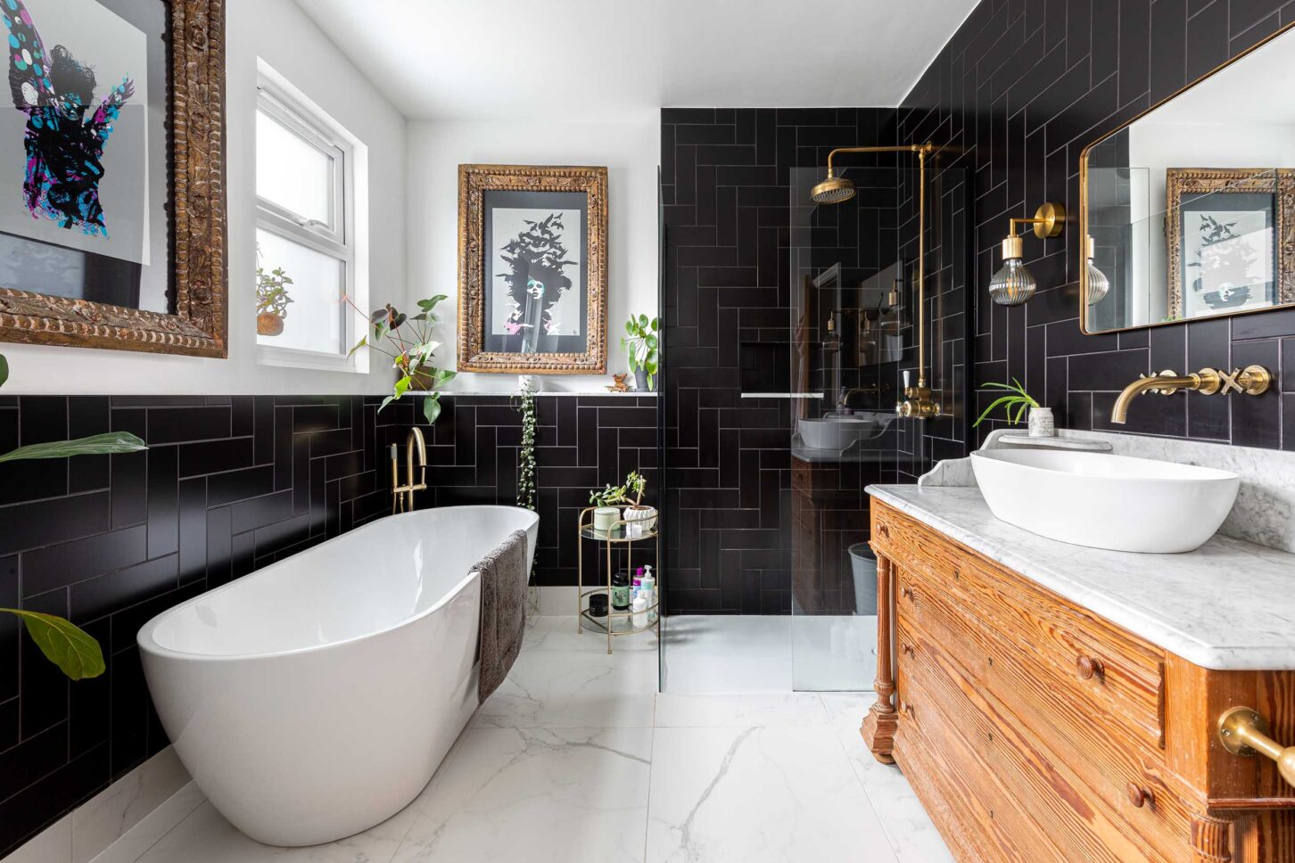 Black tiled bathroom with brass fixtures, freestanding bathtub and marble-top vanity — interior photography for Architecture:WK, London