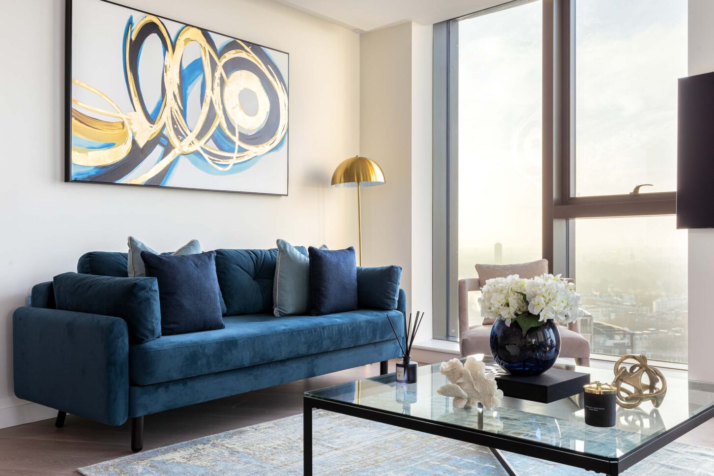 Living room with teal velvet sofa, abstract artwork and gold floor lamp overlooking London — interior photography for Housedesigner, London