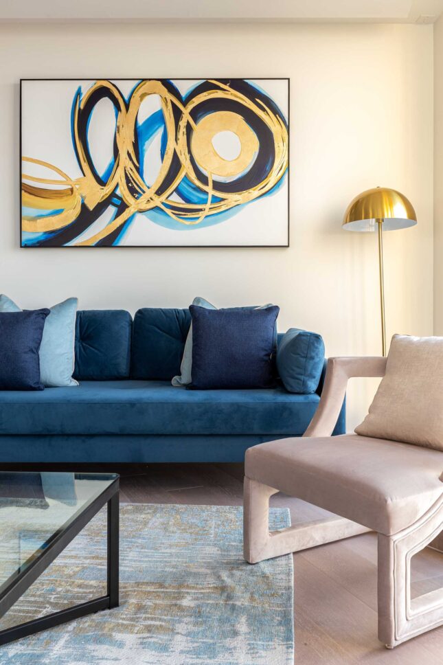 Living room detail with teal velvet sofa, blush accent chair and abstract gold artwork — Housedesigner, London