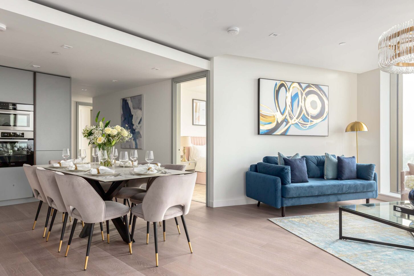 Wide view of open-plan dining and living area with teal sofa and abstract artwork — Housedesigner, London
