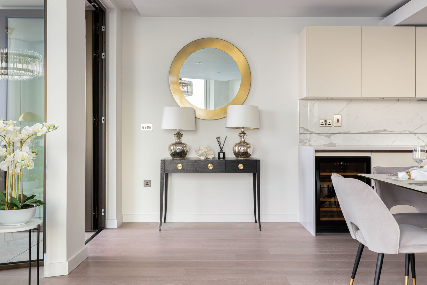 Entryway console table with round gold mirror and marble kitchen beyond — Housedesigner, London