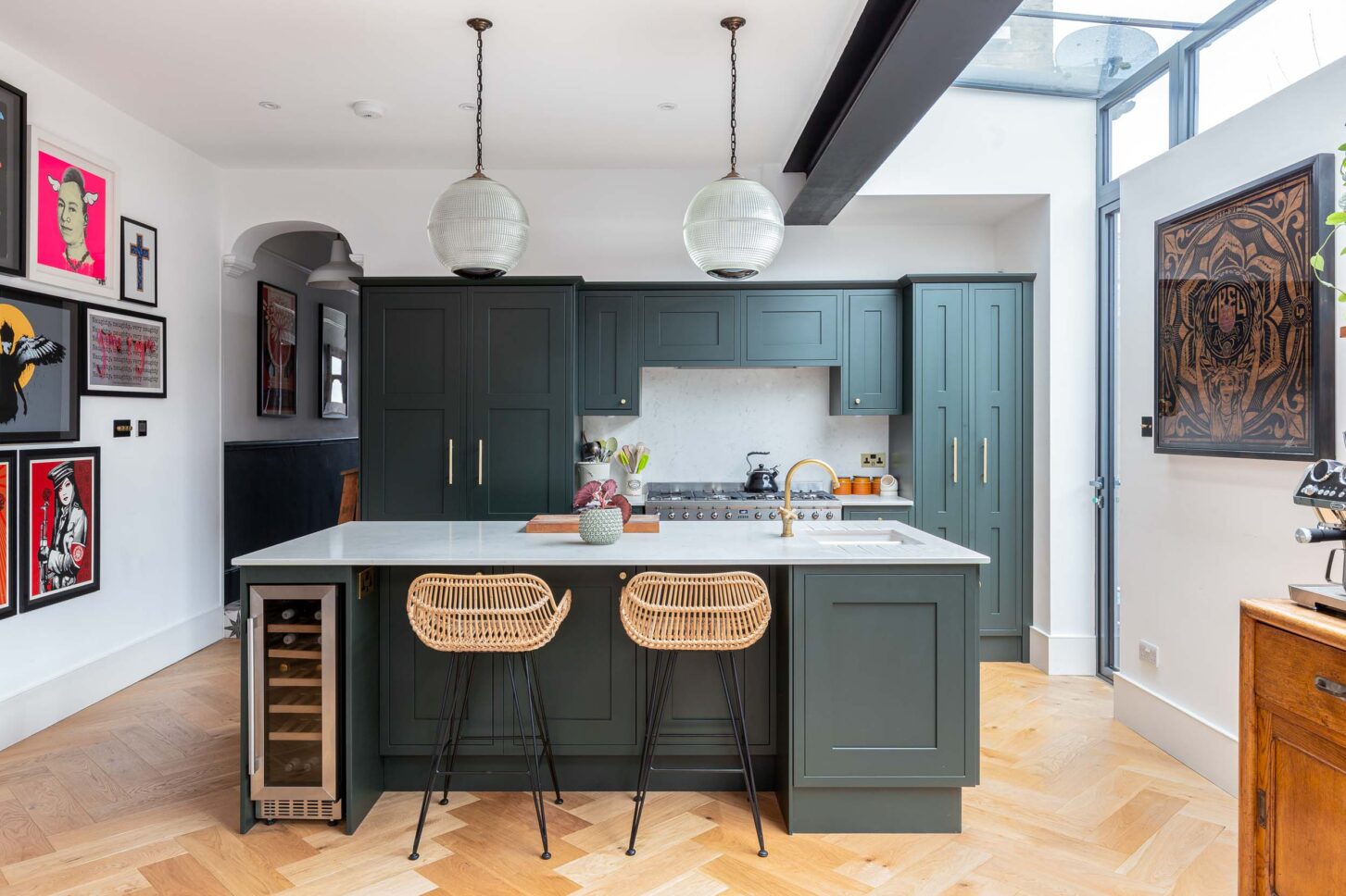 Green shaker kitchen island with rattan bar stools and glass roof extension — architectural photography for Architecture:WK, London