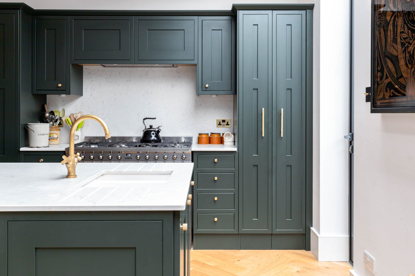 Close-up of dark green shaker cabinetry with brass tap and range cooker — interior photography for Architecture:WK, London