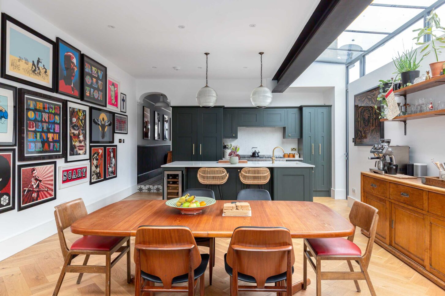Open-plan kitchen extension with vintage dining table and gallery wall of pop art prints — architectural photography for Architecture:WK, London