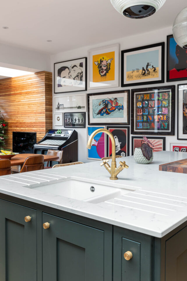 Kitchen island with brass tap and colourful gallery wall of prints — interior photography for Architecture:WK, London