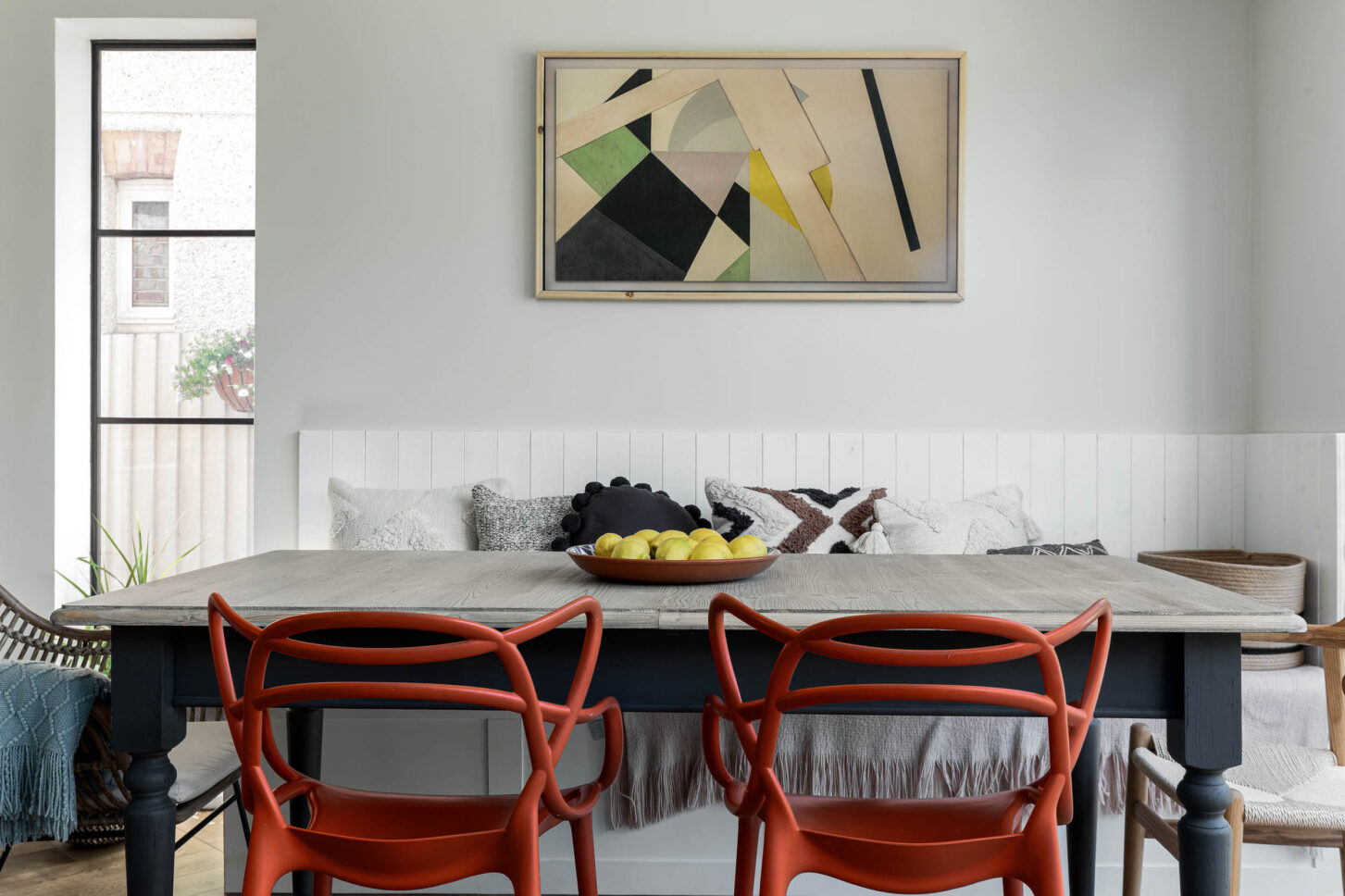 Dining table with red chairs against banquette seating — interior photographer London, Blue + Green Interiors