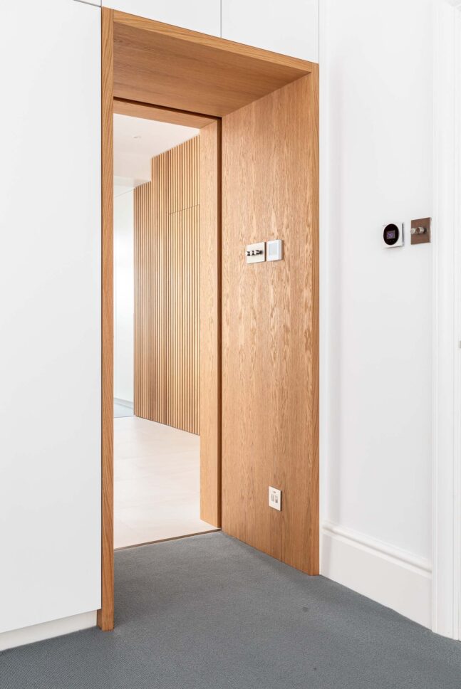 Oak door opening onto slatted timber hallway — Hoban Design, Wimbledon