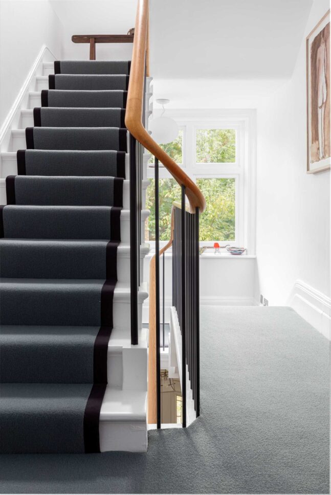 Carpeted staircase landing with curved oak handrail — interior photographer London, Hoban Design Wimbledon