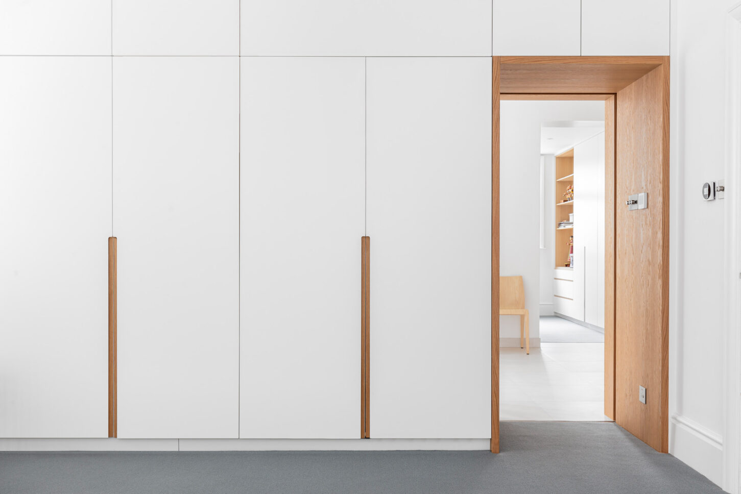 White fitted wardrobe with oak-framed doorway — interior photographer London, Hoban Design Wimbledon