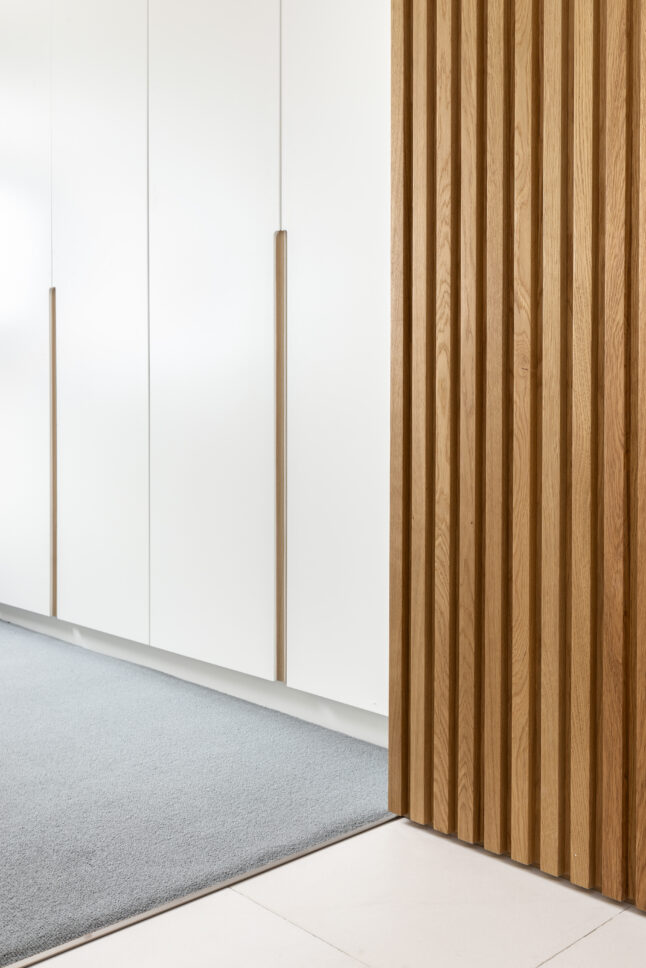Fluted oak wardrobe joinery with white panelling — Hoban Design, Wimbledon