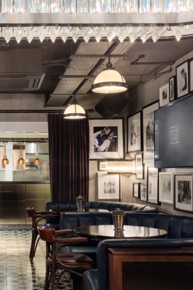 Velvet booth seating beneath crystal chandelier and gallery wall — private members' restaurant, restaurant photographer London