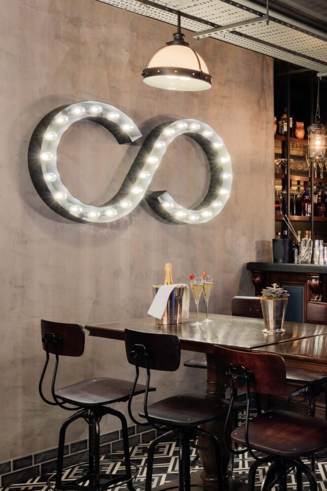 Illuminated infinity sign above table set with champagne — restaurant photographer London, private members' restaurant