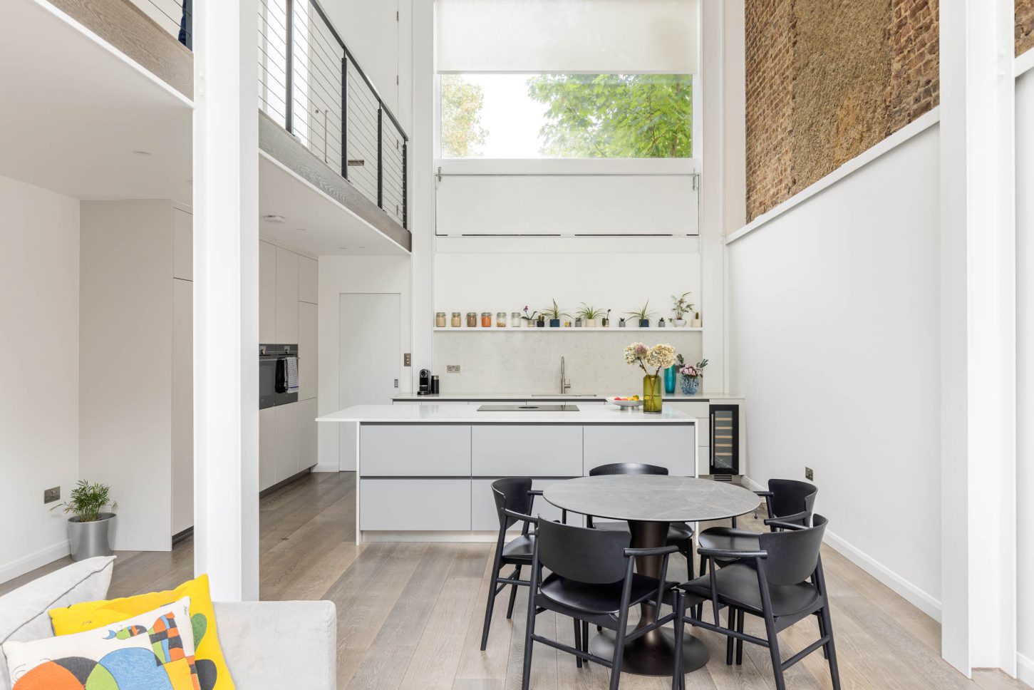 Open-plan kitchen and dining area with exposed brick wall and mezzanine — Canonbury, designed by Unknown Makers, London