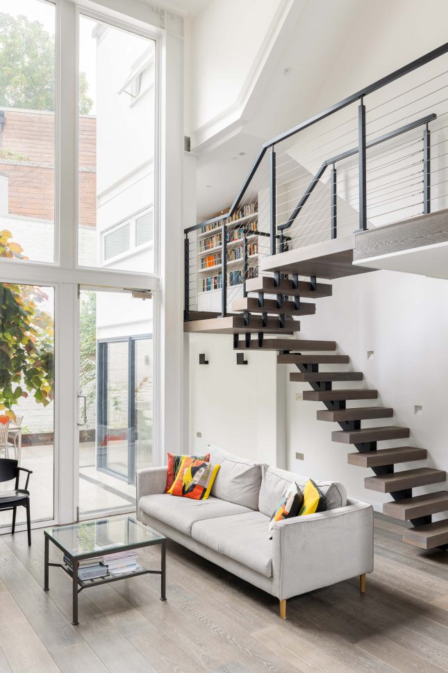 Living room and floating staircase with courtyard view through glass doors — Canonbury, designed by Unknown Makers, London