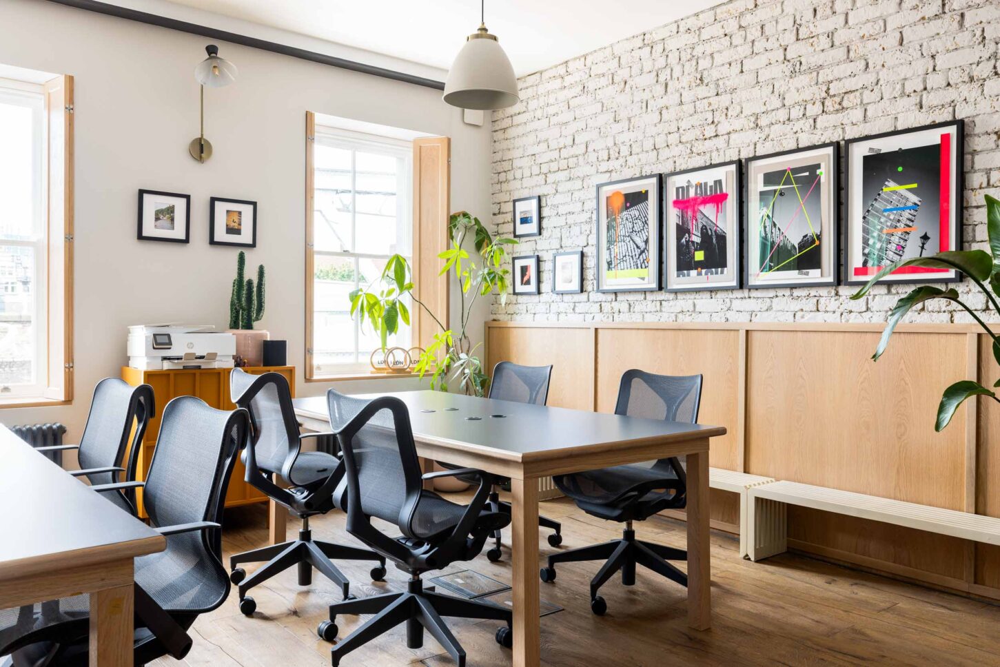 Office workspace with communal desks and brick wall art gallery, designed by Unknown Makers — Kingsland project, London