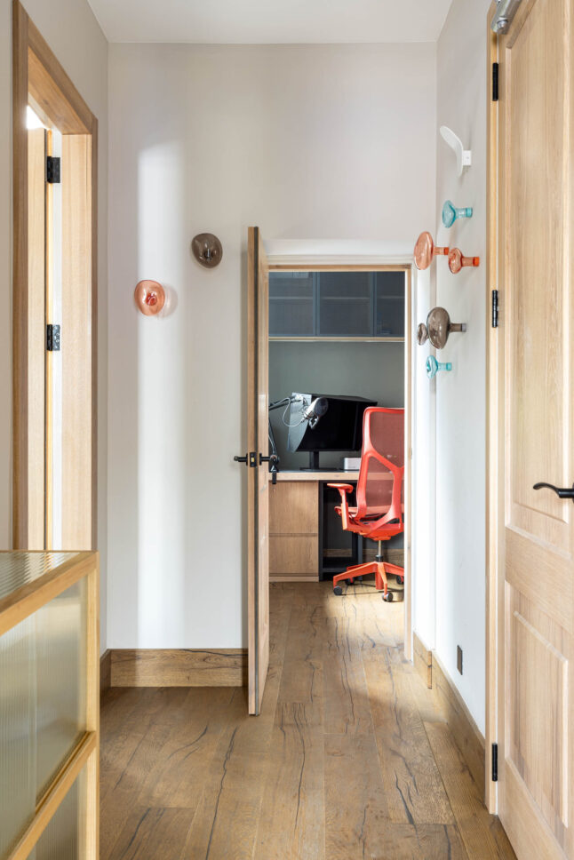 Office corridor with decorative wall hooks leading to a study nook, designed by Unknown Makers — Kingsland project, London