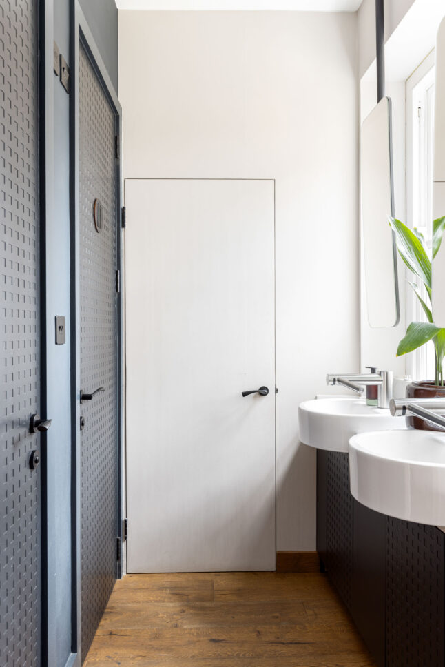 Office washroom with double sink vanity and perforated metal panels, designed by Unknown Makers — Kingsland project, London